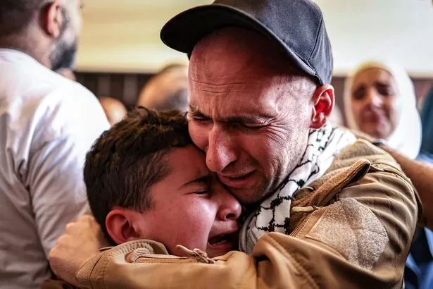 A Palestinian prisoner, released the swap, embraces a boy upon arrival at Ramallah in the occupied West Bank