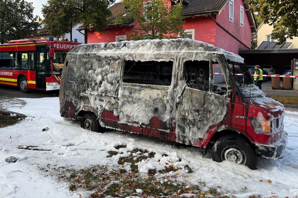 A burned van is covered by extinguishing foam after a fire in Munich