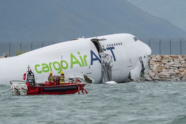 Rescue workers approach a cargo aircraft that skidded off a Hong Kong runway