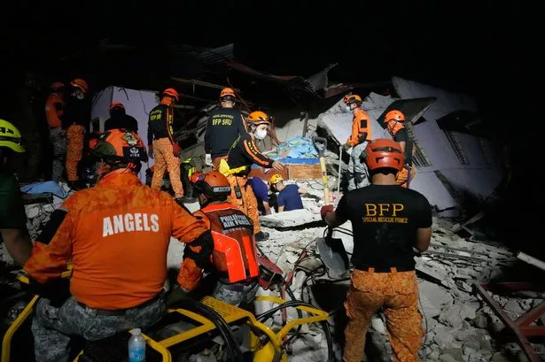 Rescuers check for survivors from the ruins of a collapsed building