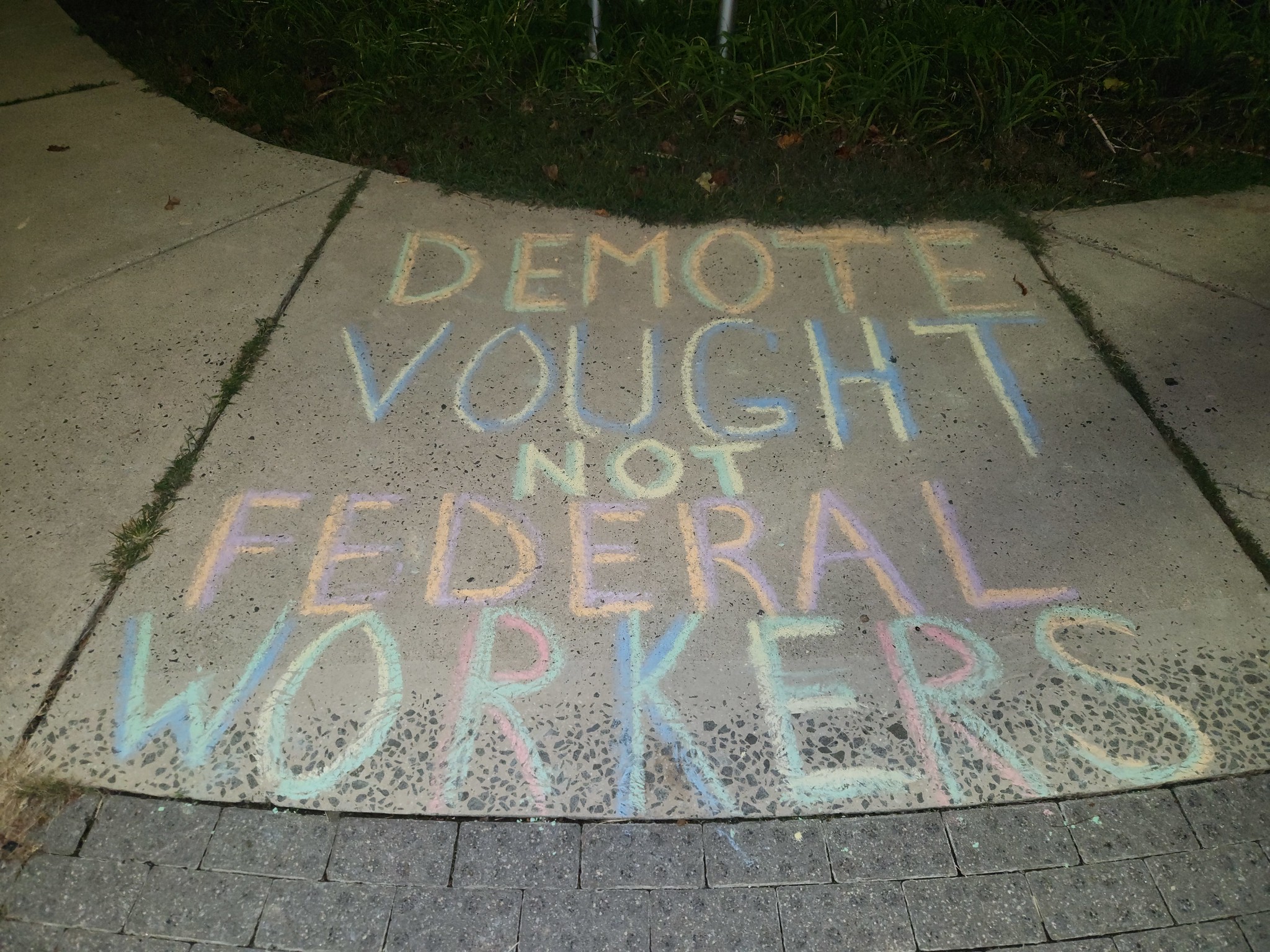 Photo of Russell Vought, a balding, bespectacled man with a beard looks to his right; overlaid on top of his photo are layers of signs showing support for federal workers.