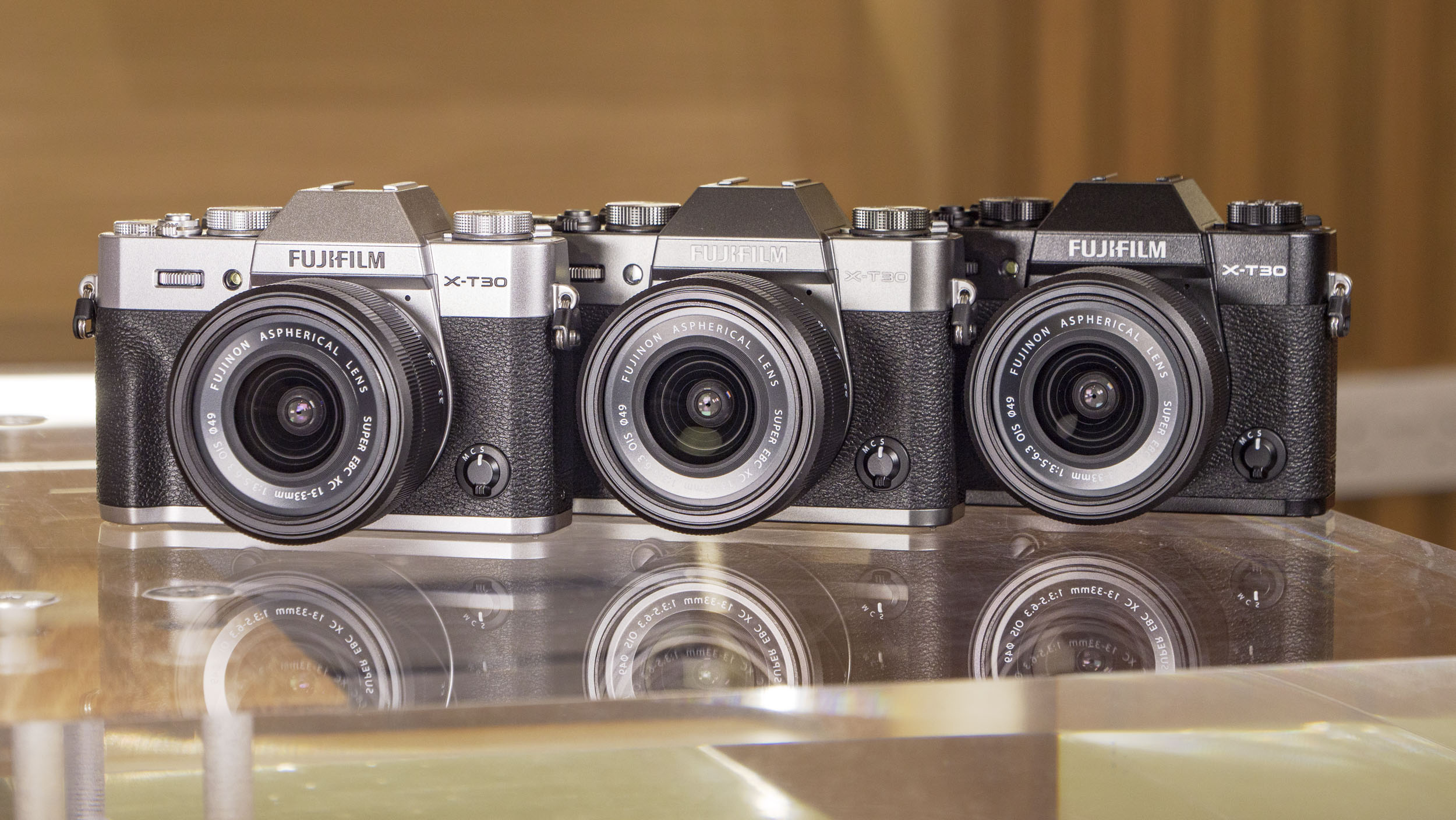 Fujifilm X-T30 III camera in three colors, on a glass table