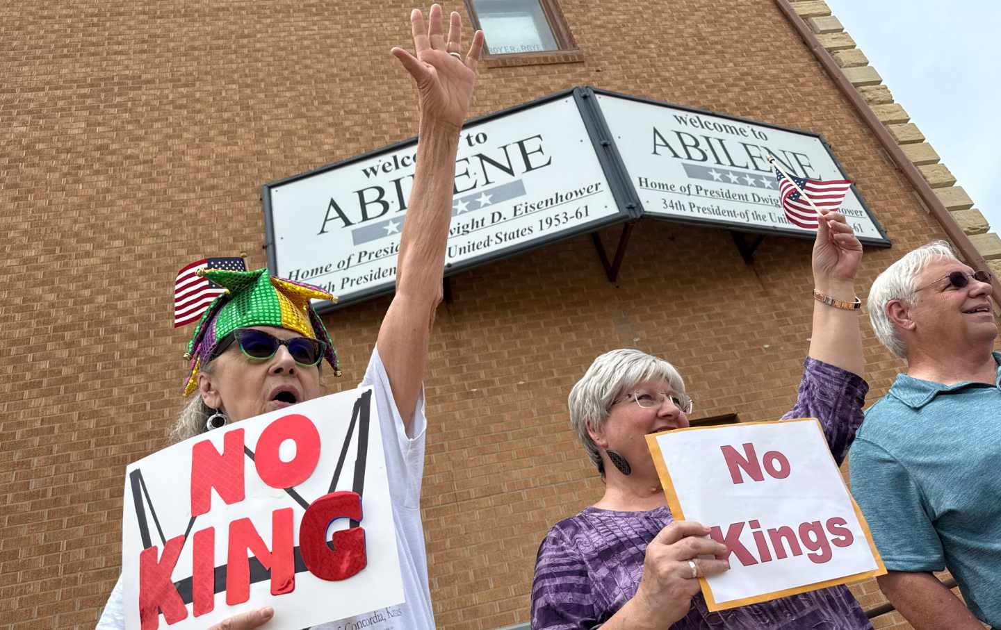 Loretta Jasper, left, and Jo Schwartz, wave to a passing vehicle on Buckeye Avenue in downtown Abilene, Kan., on Saturday, June 14, 2025, during a