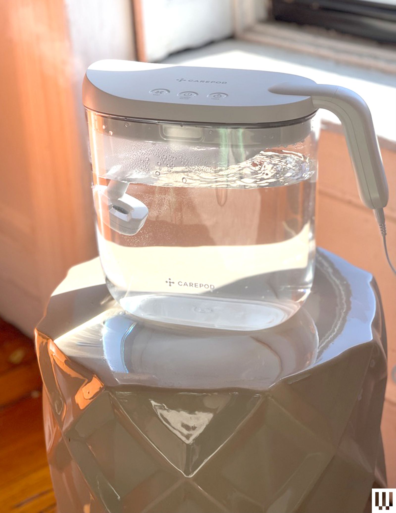 Carepod Mini Humidifier a clear container with water inside and a slightly curved handle