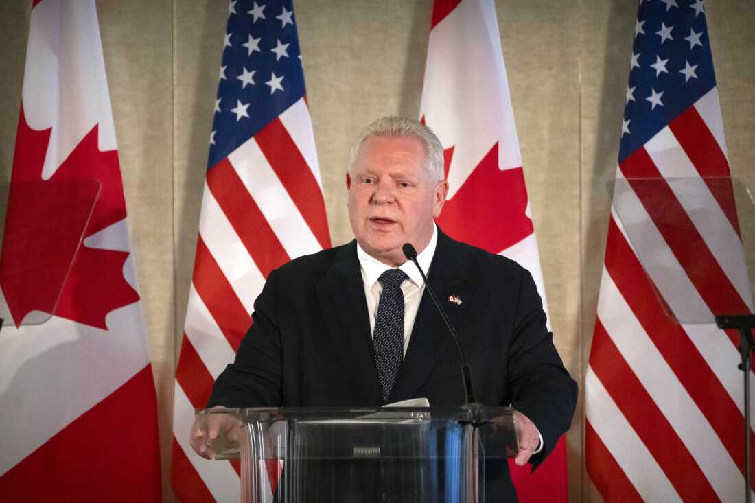 Ontario Premier Doug Ford stands at a podium in front of Canadian and U.S. flags.