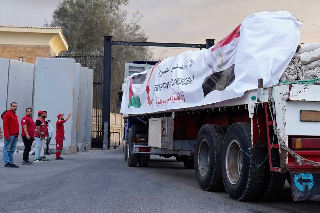 Egyptian Red Crecent members monitor trucks carrying humanitarian aid as they enter the Rafah crossing between Egypt and the Gaza Strip, following an agreement between Israel and Hamas on a ceasefire, Sunday, Oct. 12, 2025.