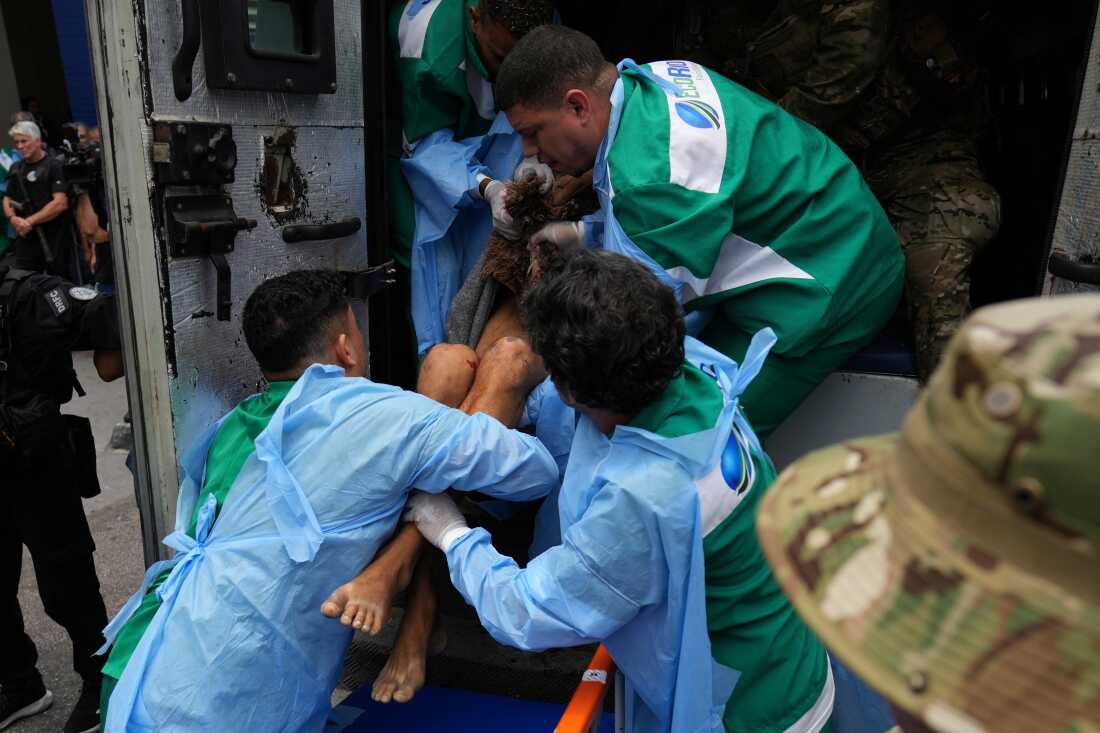 Getulio Vargas Hospital workers remove an injured person from a police truck after he was injured in a police operation against alleged drug traffickers in the Complexo do Alemao favela where the criminal organization