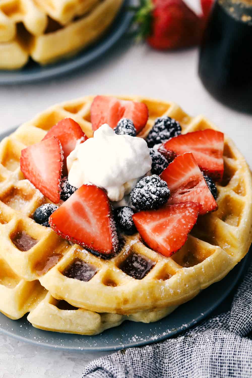 Belgian waffles with strawberries, blackberries, and whipped cream.