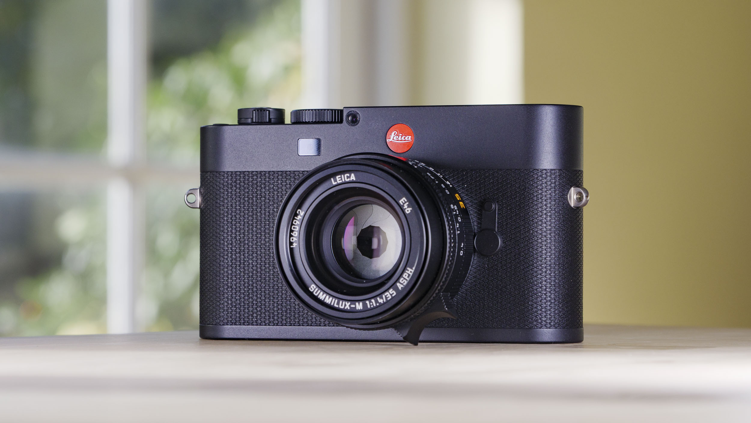 Leica M EV1 camera on a wooden table with glass-panelled door backdrop