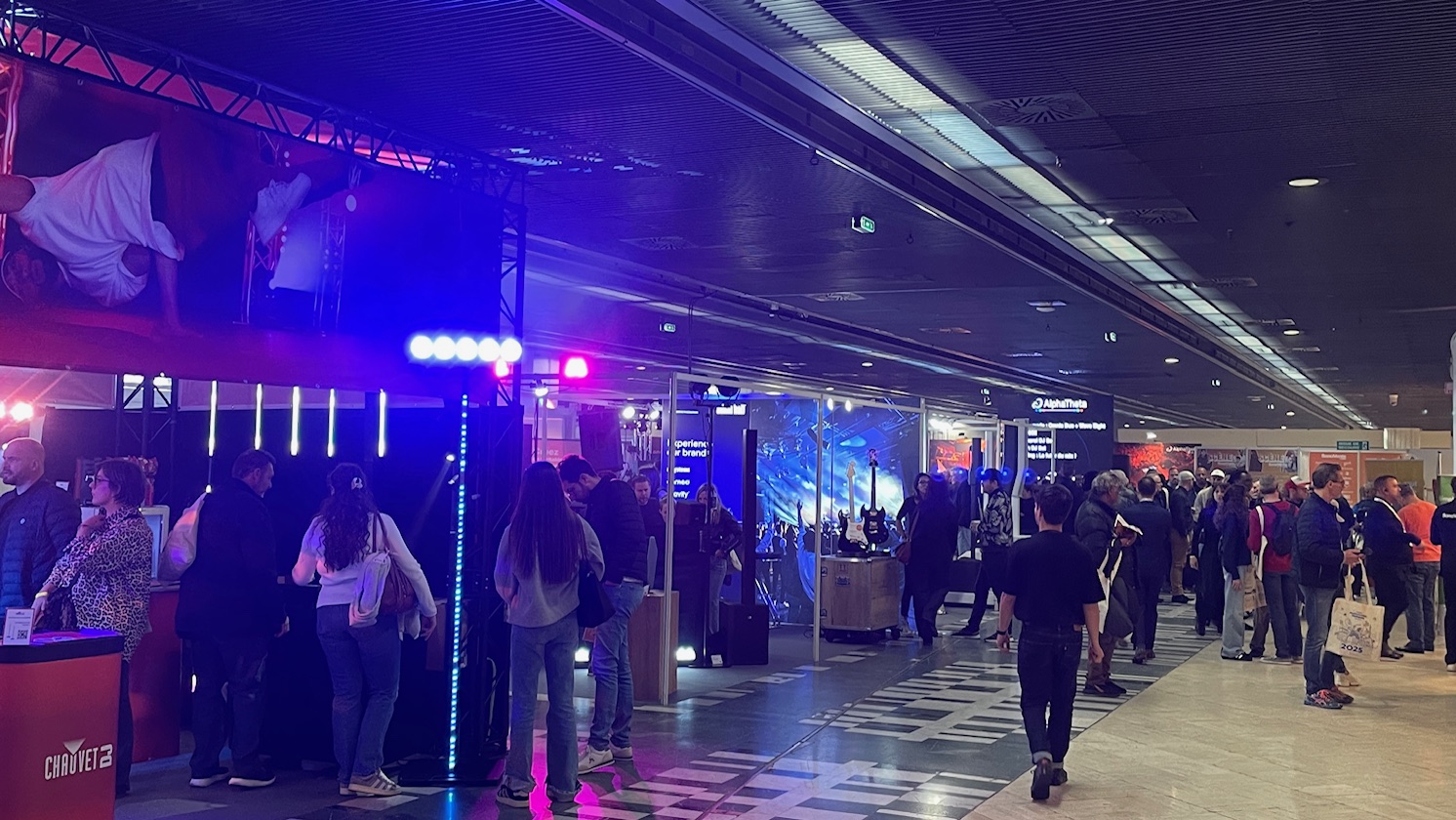 One of the halls at the Paris Audio show, lit in purple and with busy stalls