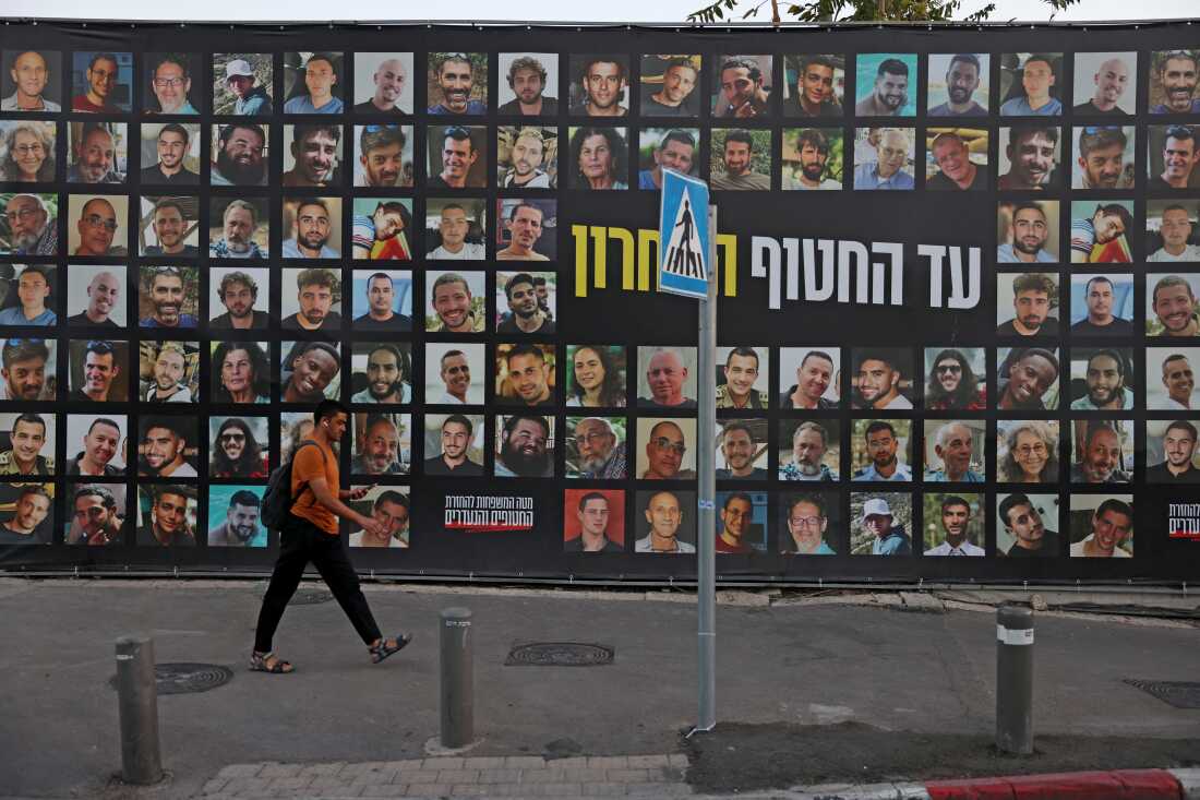 A man walks past a billboard bearing the portraits of Israelis held hostage in the Gaza Strip by Palestinian militants since Oct. 2023