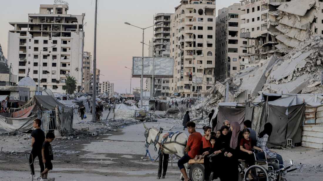 People ride a horse-drawn cart past destroyed buildings along Al-Rasheed Street in west Gaza City on Oct. 7.