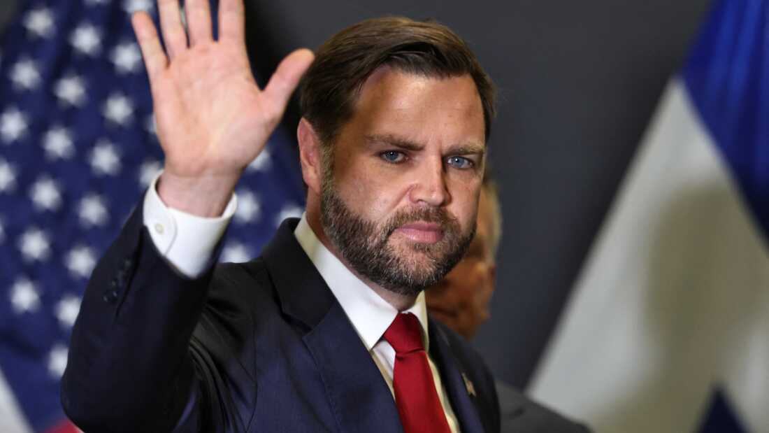 Vice President JD Vance waves as he leaves a press conference following a military briefing at the Civilian Military Coordination Center in southern Israel on Oct. 21. He is wearing a dark blue suit and a red tie.