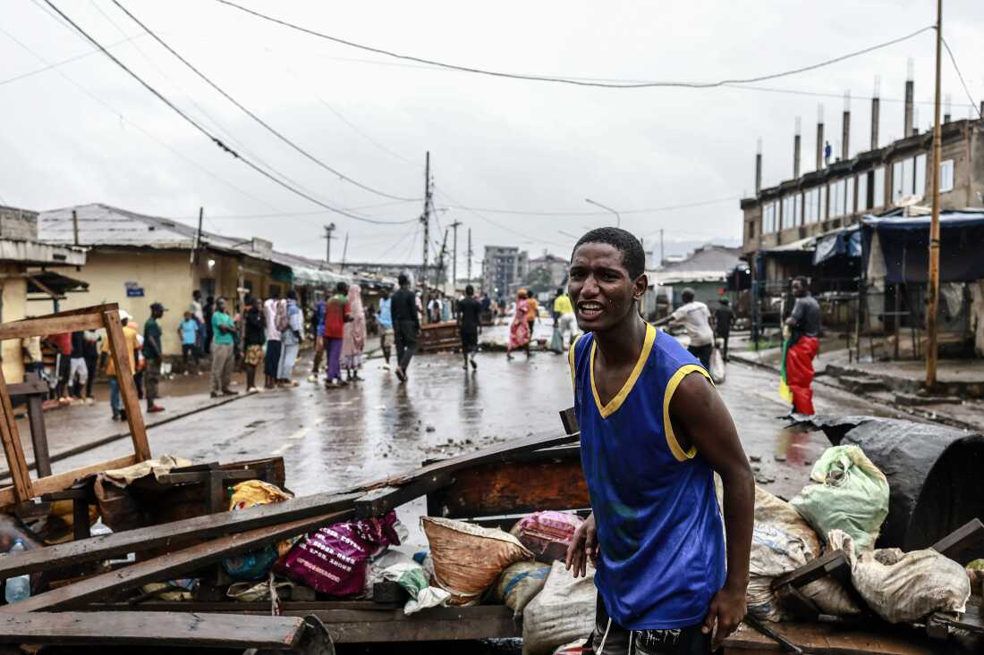 A supporter of Cameroonian opposition leader reacts as others gather materials from the streets to build barricades following the announcement of presidential election results in Yaounde on October 27, 2025.