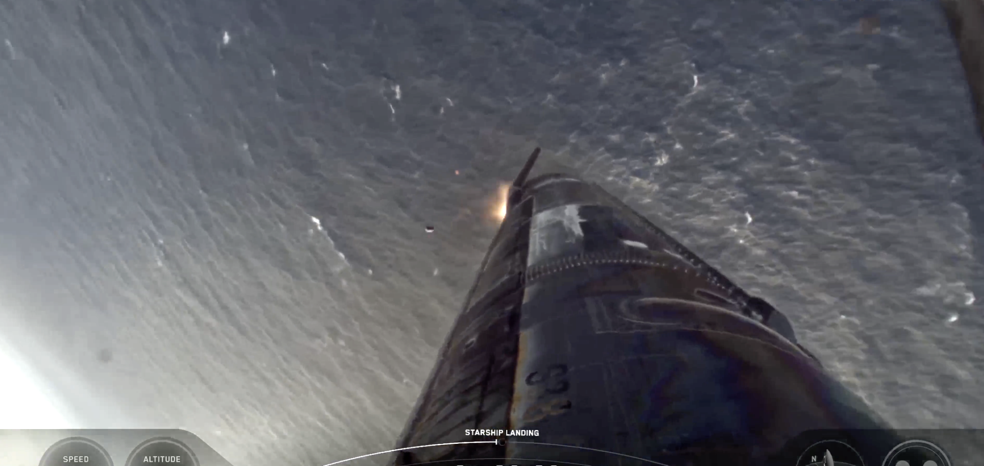 A rocket approaching the ocean with a small flame from its engine.