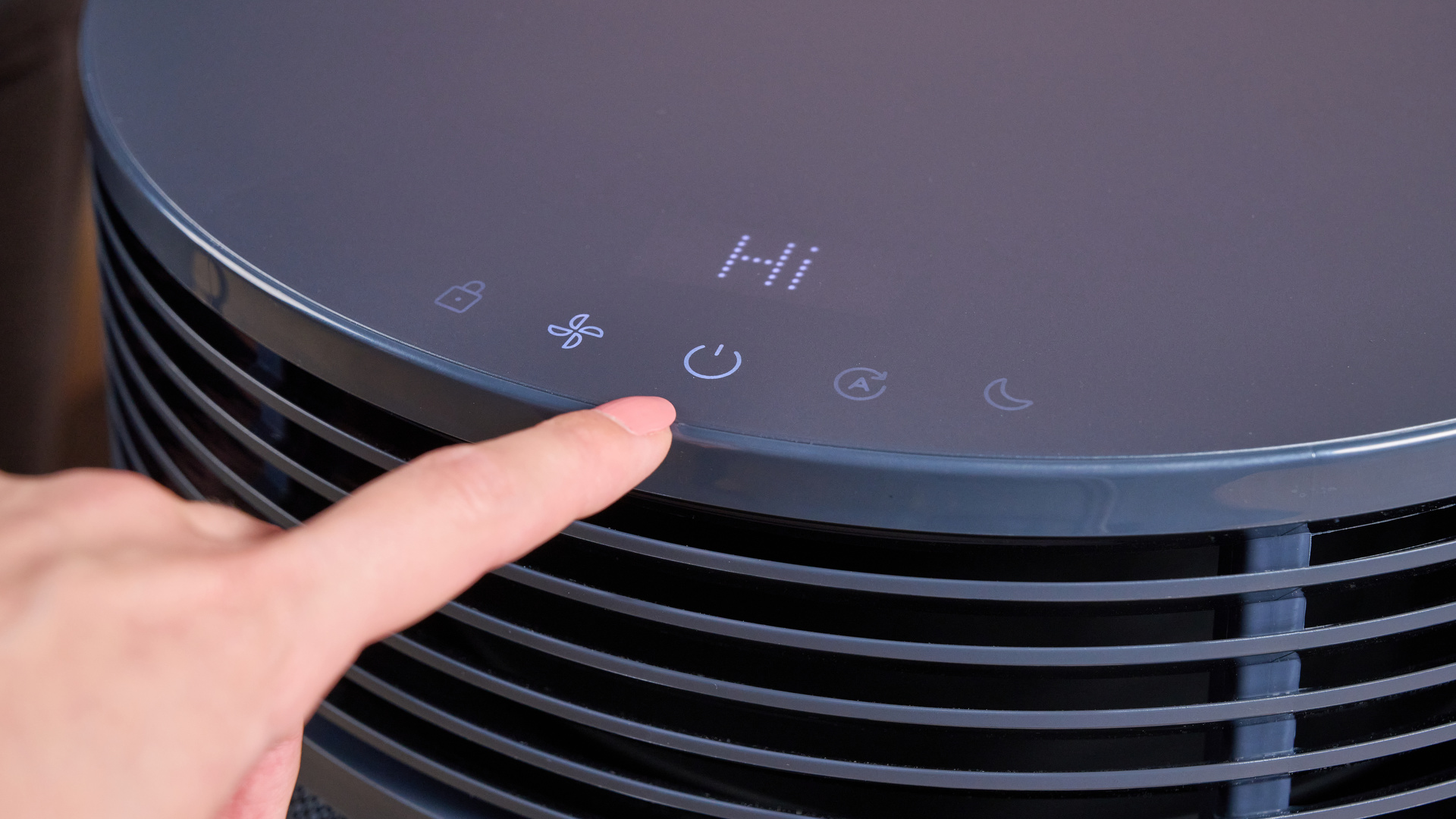 A woman has just pressed the power button on the top of the Blueair Blue Signature.