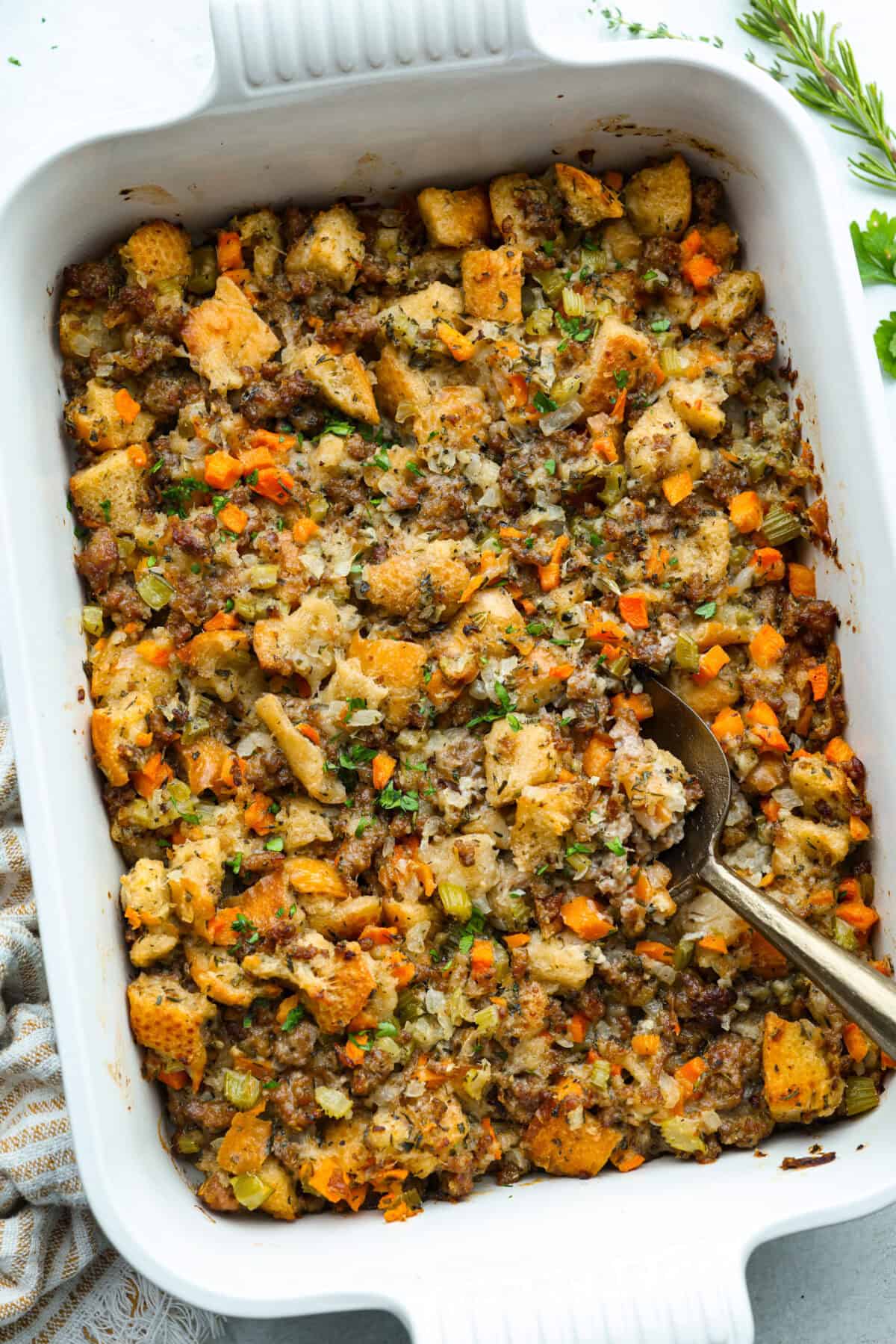 Baking dish with sourdough stuffing and a serving spoon.